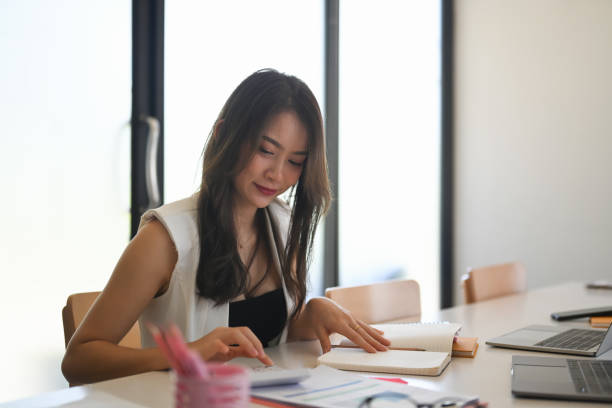 istock Young asian woman designer sitting in creative office and making noet on notebook. 1322242807