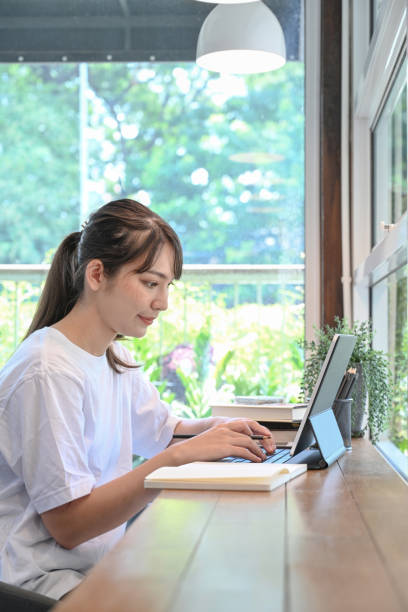 istock Side view young woman sitting in coffee shop and using computer tablet. 1322242864