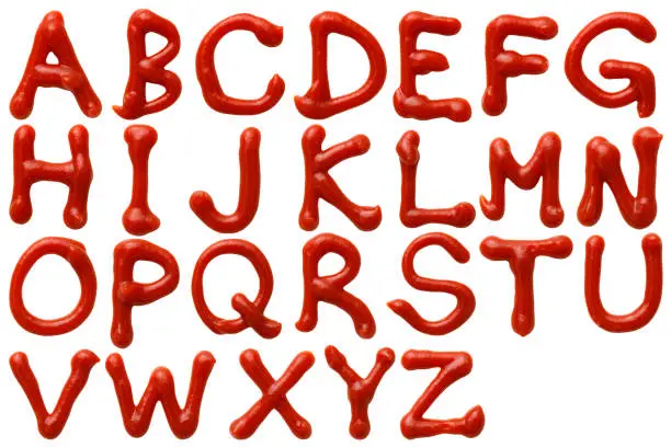 Photo of Isolated shot of upper case letters alphabetical order written in ketchup on white background