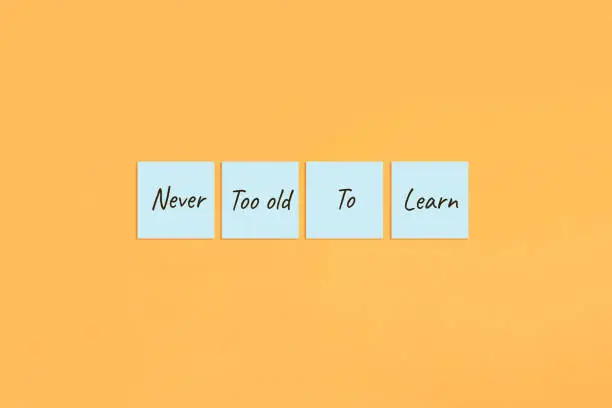 Motivational quote Never too old to learn. Handwritten inscription on sticky notes.