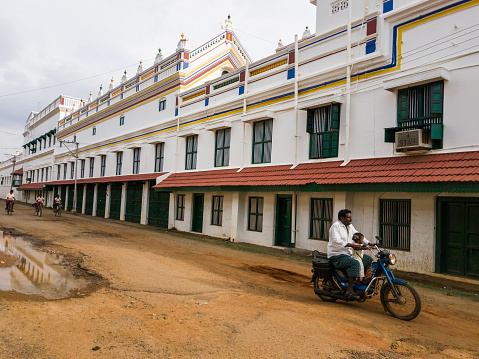 Kanadukathan, Tamil Nadu, India - January 2017: A motorcycle rides past the walls of a grand mansion in the village of Kanadukathan in Chettinadu.