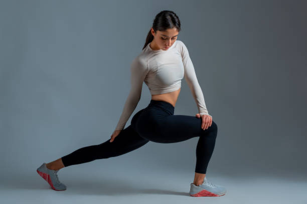 istock Girl performing lunges with body twists on grey background 1322249071
