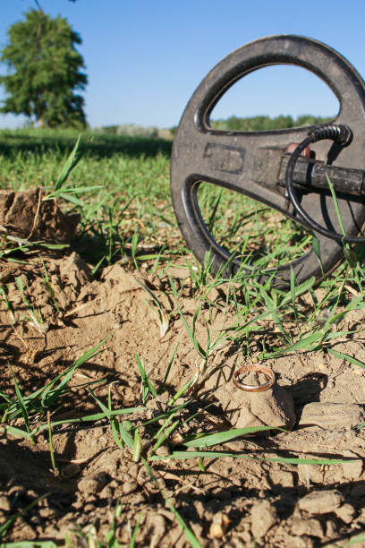 un antico anello d'oro in mano a un cercatore, trovato su un vecchio tratto con l'aiuto di un metal detector, il primo piano e lo sfondo sono sfocati con un effetto bokeh - searcher foto e immagini stock