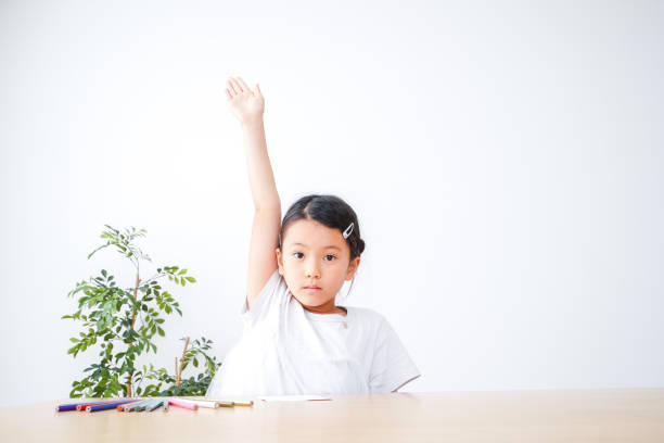 小学生の女の子がプレゼンテーションをするために手を挙げる - elementary school waist up indoors childhood ストックフォトと画像