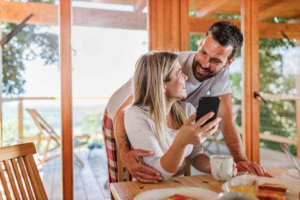 istock Happy couple using mobile phone during breakfast in the morning. 1322256075