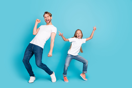 Full length portrait of two carefree cheerful persons partying chilling weekend isolated on blue color background