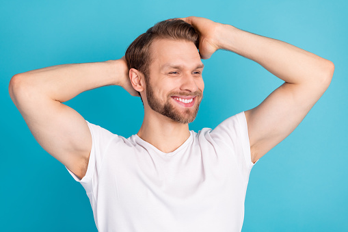 Portrait of satisfied young man hands touch enjoy hair toothy smile isolated on blue color background