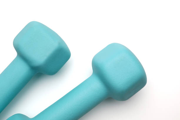 istock Two turquoise colored rubber dumbbells lying at white table 1322262230