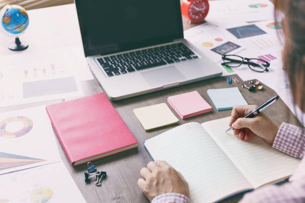 istock Business woman working at desk with laptop, post it, notebook and accessory on working desk. 1322262401