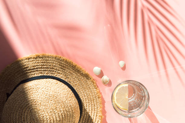 istock straw hat, water glass and shells on pink background flat lay 1322263704