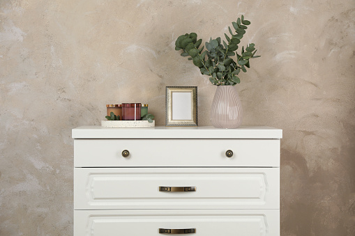 Modern chest of drawers with decor near beige wall