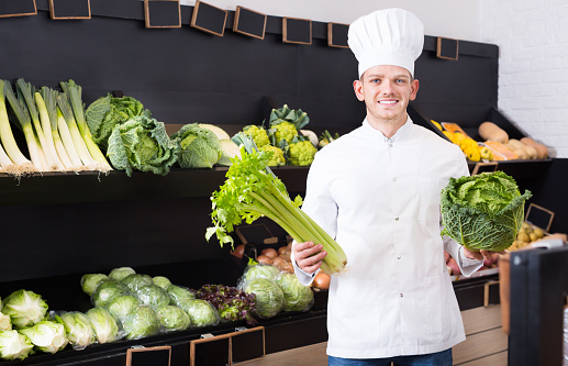 Smiling male chef looking for fresh vegetables at grocery shop