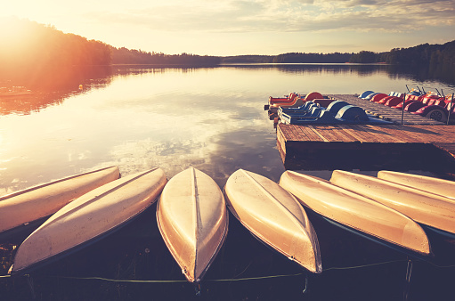 Kayaks and paddle boats by a lake at sunset.