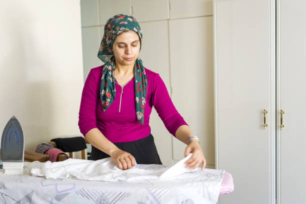 istock Young woman working with iron on ironing board 1322275846