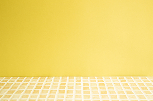 Yellow ceramic mosaic tile table. yellow wall background. Home interior