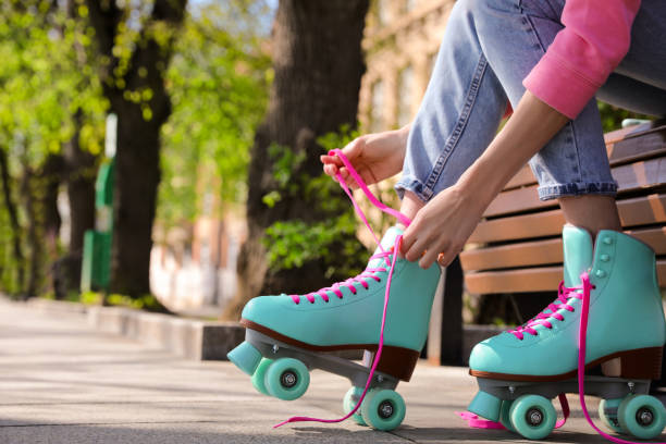 frau schnüren rollschuhe, während sitzen auf der bank im freien, nahaufnahme - schlittschuh oder rollschuh stock-fotos und bilder