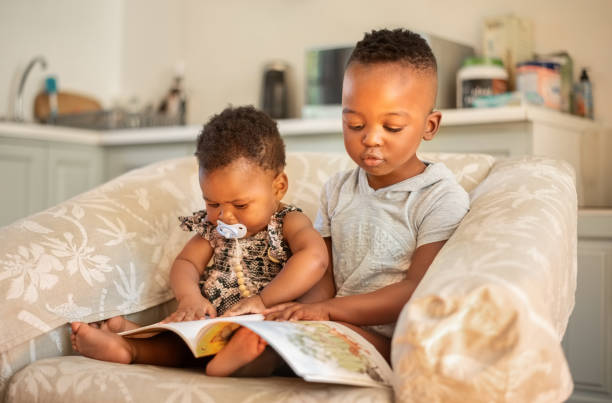 irmãos assistindo livros educativos infantis em casa - africa child reading african descent - fotografias e filmes do acervo