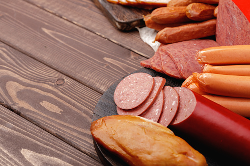 Variety of meat and sausage products on wooden table