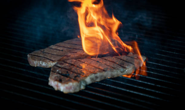 istock Two pieces of Striploin beef tips on getting grilled on a barbeque grill.GRILLING 1322279090