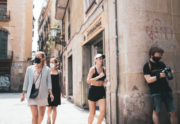 mujer corredora pasa por turistas desenmascarados en pandemia - unmasked fotografías e imágenes de stock