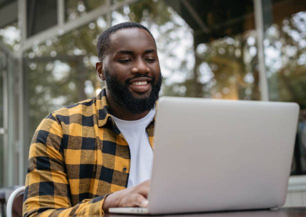 istock Smiling copywriter working freelance project, typing on keyboard, sitting at workplace. Portrait of handsome African American programmer using laptop computer 1322285170