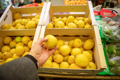 man hands taking lemon in groceries store copy space