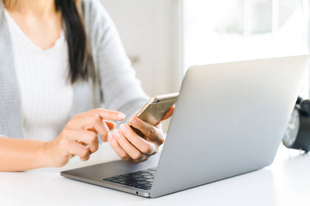 istock young woman using mobile phone with a laptop computer. 1322286993