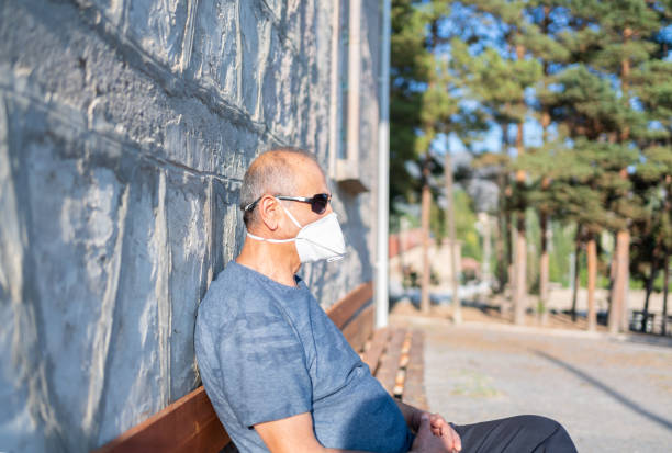 istock Senior Man With Protective Face Mask Sitting On A Bench 1322287964