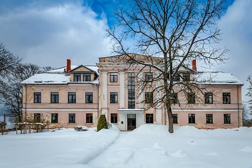 An exterior view of an abandoned school on a winter afternoon in Zentene, Latvia.