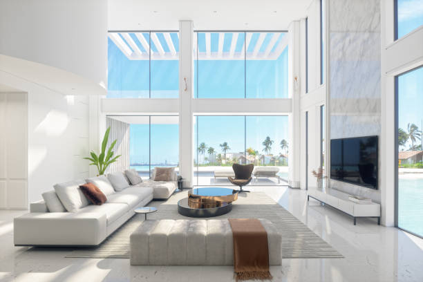 Luxury Modern Living Room Interior With Panoramic Sea View Large and luxurious interior of a fully furnished modern living room with panoramic sea and beach view. wide window stock pictures, royalty-free photos & images