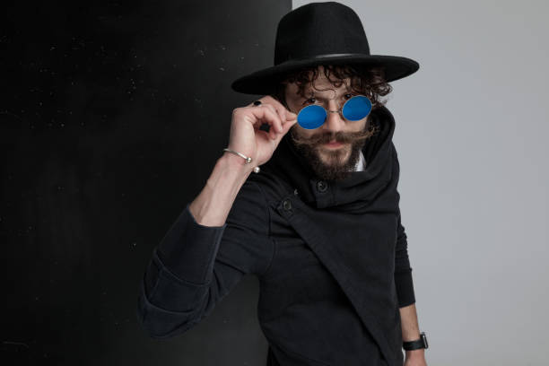 istock attractive bearded man with black hat looking over glasses 1322297237