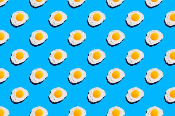 Fried egg pattern on bright blue background. Abstract background food pattern.