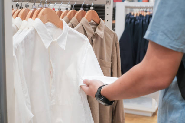 Man hands choosing Trendy cotton Men shirt display on mannequin in clothes shop. stock photo