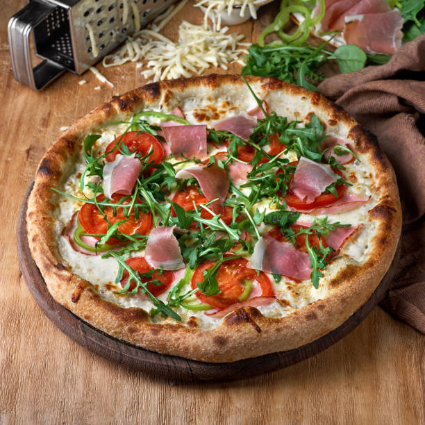 Pizza with prosciutto parma ham, arugula salad on wooden background.