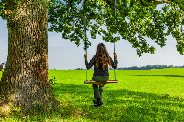 Woman on a swing by an oak tree