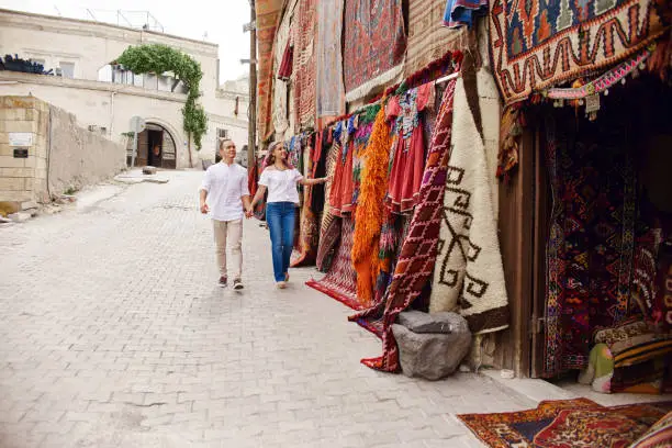 Photo of Couple in love buys a carpet and handmade textiles at an oriental market in Turkey. Hugs and cheerful happy faces of men and women