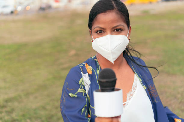 istock Female journalist wearing mask holding microphone 1322310157