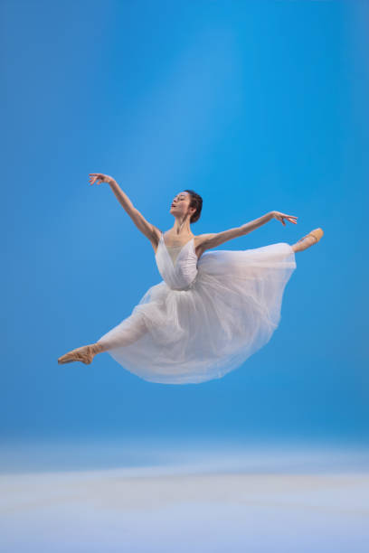 istock Young and graceful ballet dancer isolated on blue studio background. Art, motion, action, flexibility, inspiration concept. 1322311055