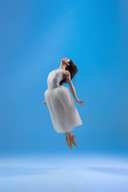 istock Young and graceful ballet dancer isolated on blue studio background. Art, motion, action, flexibility, inspiration concept. 1322311073