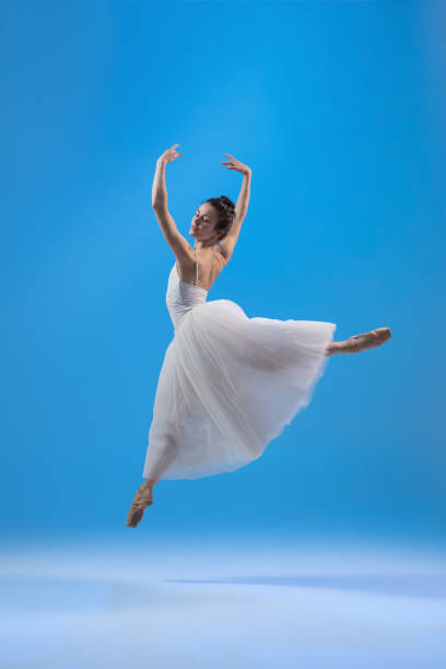 istock Young and graceful ballet dancer isolated on blue studio background. Art, motion, action, flexibility, inspiration concept. 1322311077