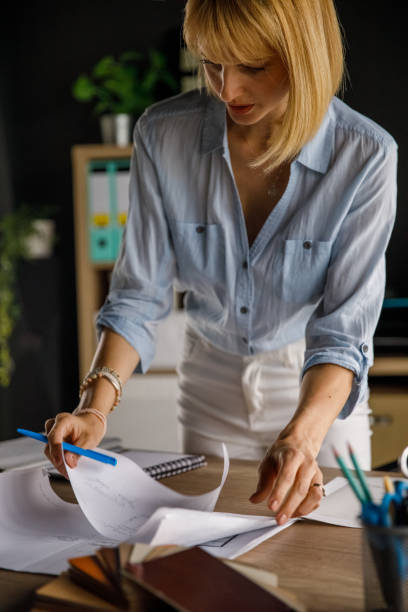 istock Female architect organizing blueprints and documents on her desk 1322318084