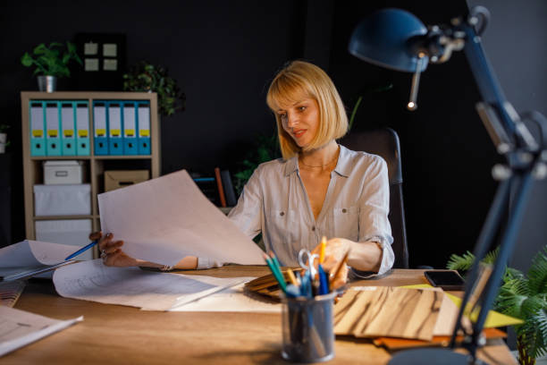 istock Female architect reviewing blueprint plans at her desk 1322318330