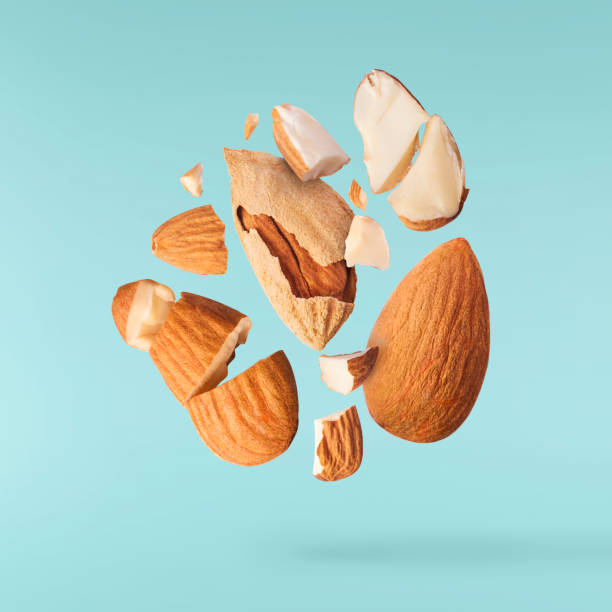Fresh raw almond. Organic healthy snack Flying in air fresh raw whole and cut almonds  isolated on turquoise background. Concept of Almonds is torn to pieces close-up. High resolution image almond tree stock pictures, royalty-free photos & images