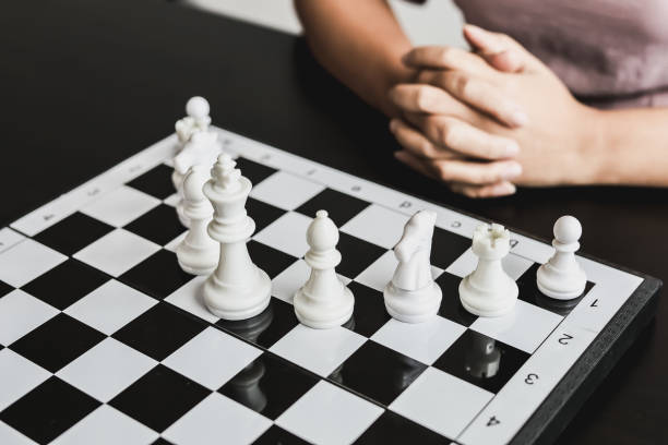 White chess pictures laid out on a chessboard, concept comparing playing chessboard to business administration. Businessmen playing chess are likened to business planning and problem-solving. imágenes de ajedrez blanco dispuestas en un tablero de ajedrez, concepto que compara el tablero de ajedrez con la administración de empresas. los hombres de negocios que juegan al ajedrez se ven en comparación con la planificación empresarial y la reso