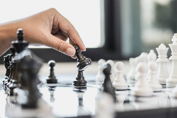 istock A businesswoman holding a black chess piece walks forward on a chessboard, comparing the chessboard to business administration, planning operations to achieve goals and solve business problems. 1322322580