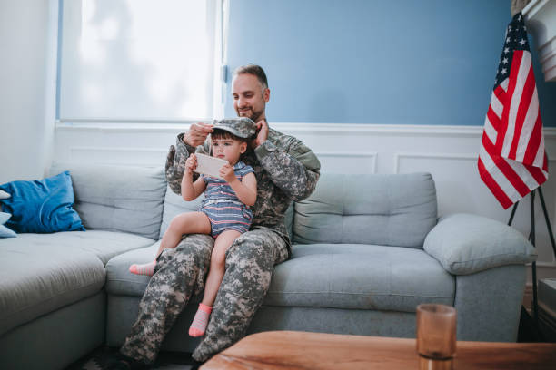 istock Happy father soldier and daughter using phone together 1322328616