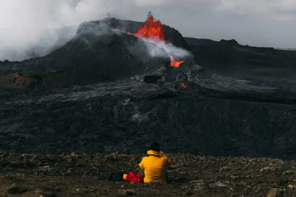 Photo of Man traveler feeling awe looking at Fagradalsfjall volcanic eruption in Iceland