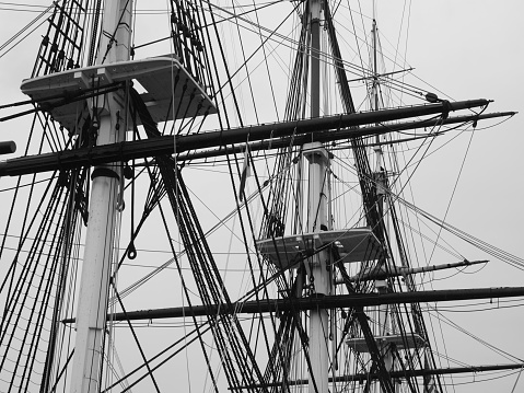 Monochromatic image of a bunch of tall masts of an old sailing-vessel.