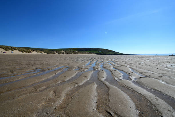 Ripples in the sand at Croyde Bay Devon. The photo is taken with a wide angle lens. The rippled sand fill the foreground and stretch to the distance. The sky is blue. The photo is taken at Croyde Bay which is a famous surfing beach in north Devon. It is situated in the south-west of the UK in an area often known as the West Country. It is a tourist destination. The photo was taken in April 2021. croyde bay photos stock pictures, royalty-free photos & images