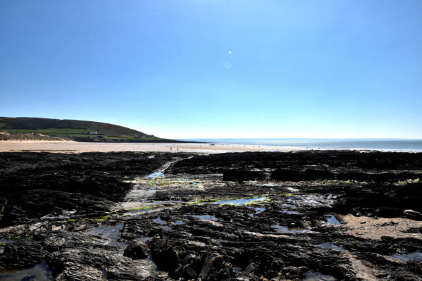 Rock pools at Croyde Beach Devon The photo is taken with a wide angle lens. The rocks pools fill the foreground and stretch to the distance. The sky is blue. The sand of the beach can be seen in the top of the photo. The photo is taken at Croyde Bay which is a famous surfing beach in north Devon. It is situated in the south-west of the UK in an area often known as the West Country. It is a tourist destination. The photo was taken in April 2021. croyde bay photos stock pictures, royalty-free photos & images
